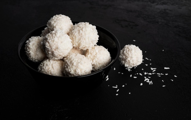 Caramelle al cocco con noci su sfondo scuro Raffaello su sfondo nero Foto di alta qualità