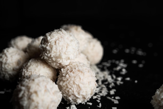 Caramelle al cocco con noci su sfondo scuro Raffaello su sfondo nero Foto di alta qualità