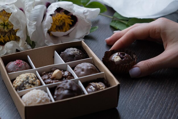 Caramelle artigianali al cioccolato in mano femminile e scatola di caramelle