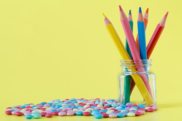 Caramelle colorate e vaso su una parete gialla