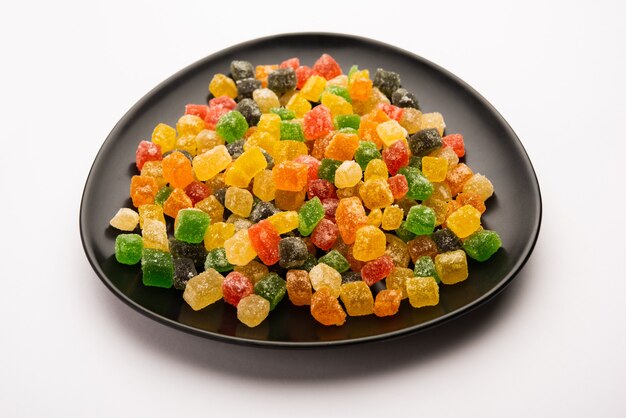 Caramelle colorate indiane e morsi di gelatina dolci al gusto di frutta ricoperti di zucchero, serviti in un piatto o in una ciotola