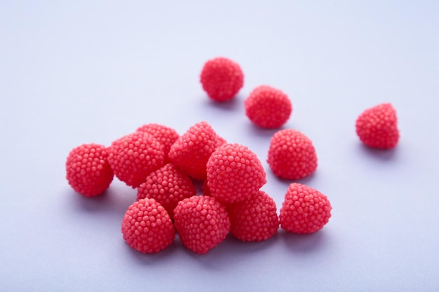 Caramelle da masticare rosse a forma di bacche Caramelle a forma di lamponi su sfondo viola Spazio per il testo
