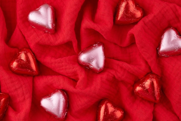 caramelle di cioccolato a forma di cuore rosse e rosa su sfondo di tessuto rosso