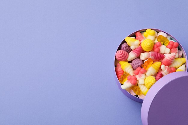 Caramelle di gelatina in scatola su sfondo viola spazio per il testo