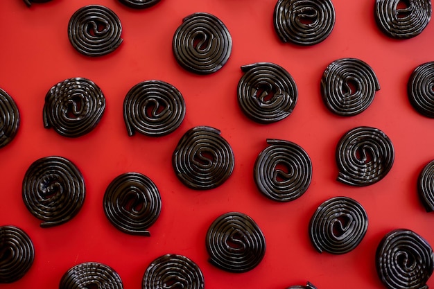 Caramelle di liquirizia nera gustose piatte su sfondo rosso