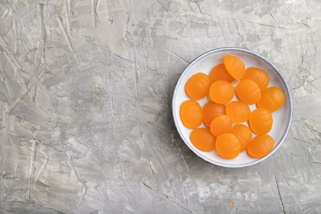 Caramelle di zucca gelatina su sfondo grigio cemento