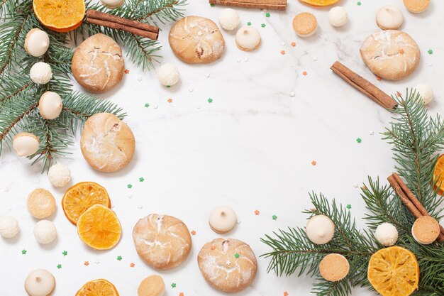 Caramelle e biscotti con rami di albero di Natale su sfondo di marmo bianco