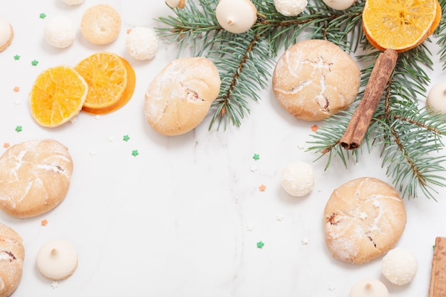 Caramelle e biscotti con rami di albero di Natale su sfondo di marmo bianco