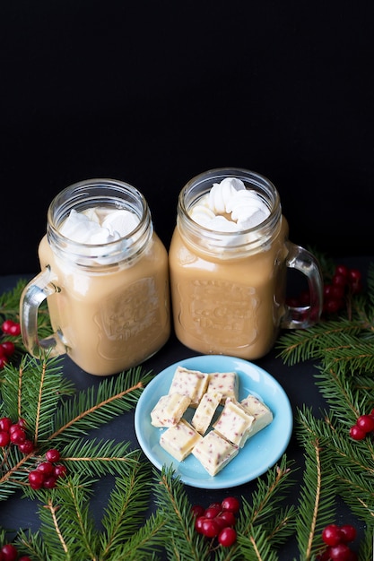 Caramelle e cacao con marshmallow su uno sfondo nero con cioccolato bianco