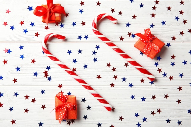 Caramelle e coriandoli di Natale su fondo di legno bianco