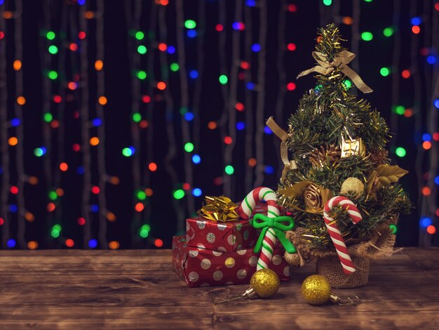 Caramelle e regali di Natale sotto un albero di abete rosso decorato.