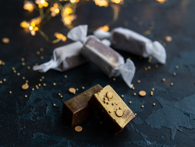 Caramelle fresche caramello caramello d'oro nel libro bianco su sfondo blu scuro con ghirlanda a forma di stelle luminose.