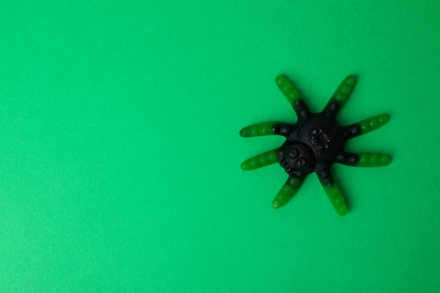 Caramelle gommose a forma di ragno su sfondo verde.