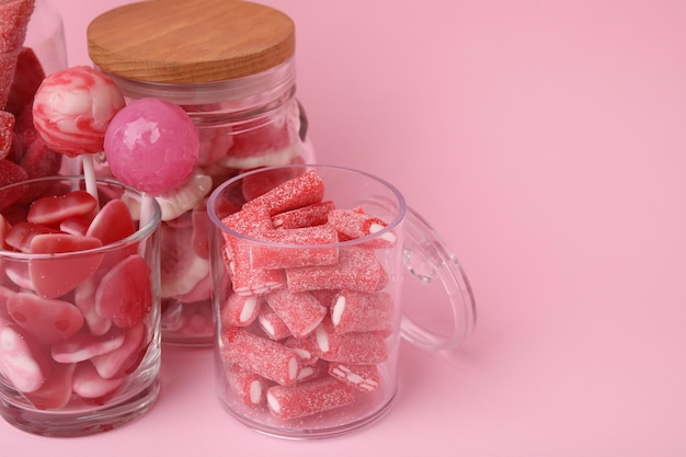 Caramelle gustose in barattoli di vetro su sfondo rosa in primo piano Spazio per il testo