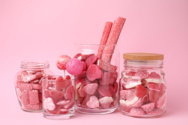 Caramelle gustose in barattoli di vetro su uno sfondo rosa