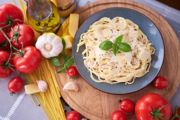 Carbonara di pasta fatta in casa con basilico fresco e parmigiano in piatto di ceramica