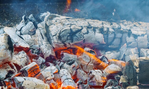 Carbone ardente nel pozzo della griglia del BBQ isolato su fondo nero