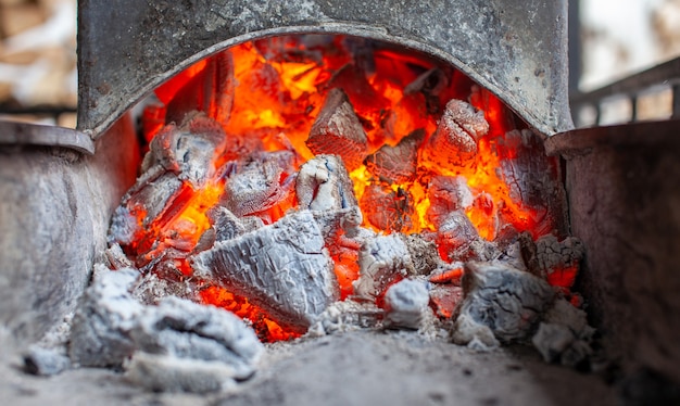 Carboni ardenti in una griglia metallica per friggere carne e verdure. Cucinare su un fuoco da campo.