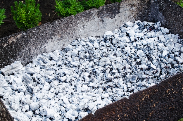 Carboni bruciati grigi in un barbecue. Falò per un picnic. Estate, giornata di sole all'aperto.