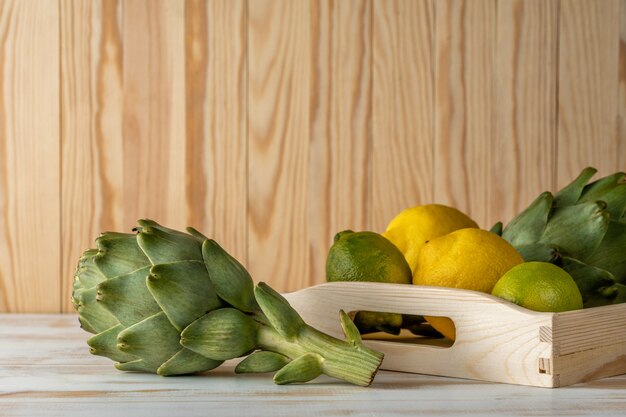 Carciofi organici maturi su una tavola di legno bianca con il limone.