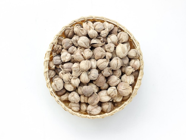 Cardamomo o Kapulaga su sfondo di tela bianca. Semi secchi. Spezie alle erbe essiccate.