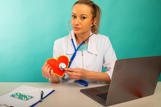 Cardiologo che tiene il modello del cuore e lo stetoscopio nel suo concetto di attacco di cuore dell'ufficio