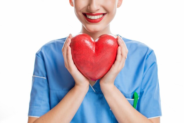 Cardiologo femminile in uniforme che tiene cuore rosso isolato su sfondo bianco