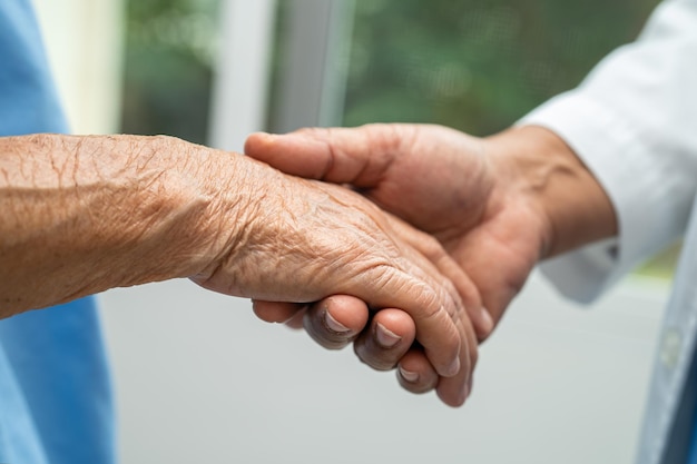 Caregiver che si tiene per mano Donna anziana asiatica paziente con amore cura incoraggiare ed empatia