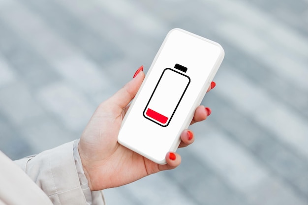 Carica bassa della batteria del telefono cellulare Mano femminile che tiene uno smartphone a bassa carica