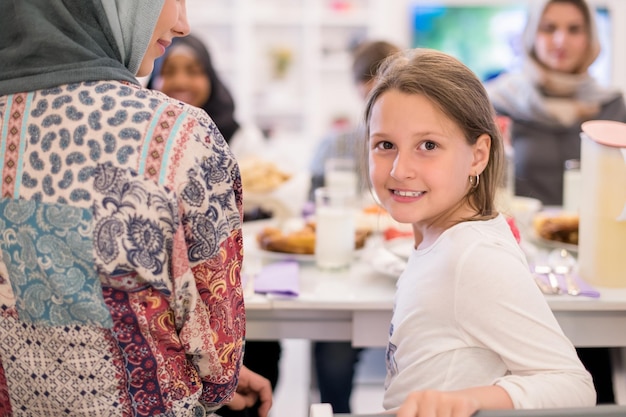 carina bambina che si gode la cena iftar insieme alla moderna famiglia musulmana multietnica sullo sfondo durante una festa del ramadan a casa