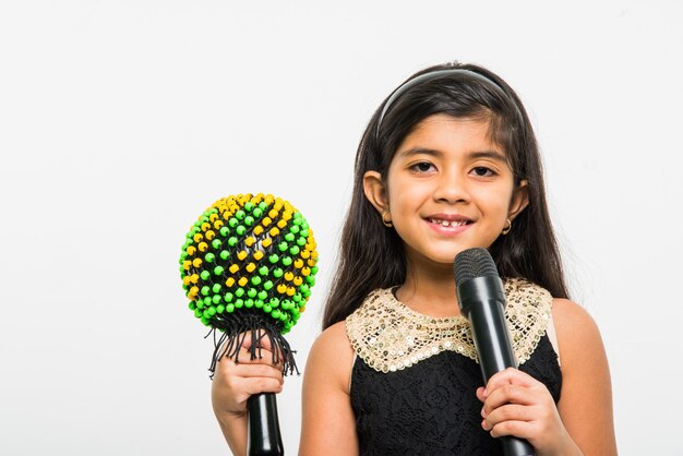 Carina bambina indiana che canta nel microfono, isolata su sfondo bianco