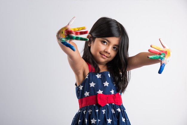 Carina bambina indiana che mostra le sue mani colorate o la stampa del palmo o la pittura o gioca al festival di holi con i colori, isolato su sfondo bianco