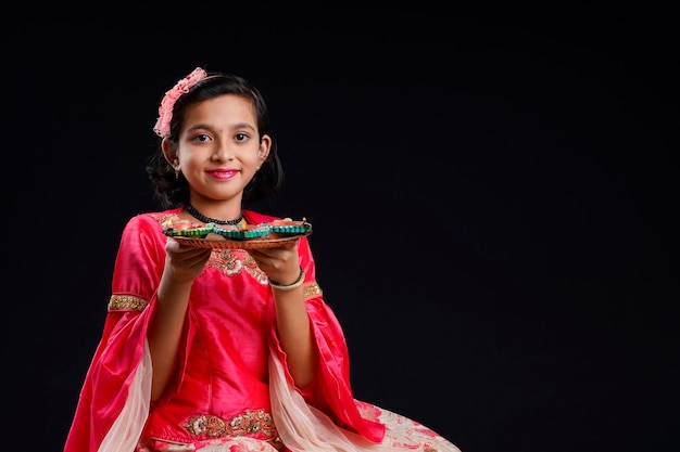 Carina bambina indiana che tiene diya o lampade a olio per la celebrazione del Diwali.