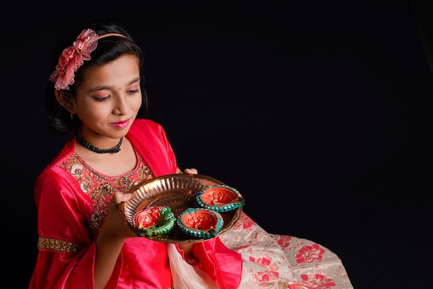 Carina bambina indiana che tiene diya o lampade a olio per la celebrazione del Diwali.