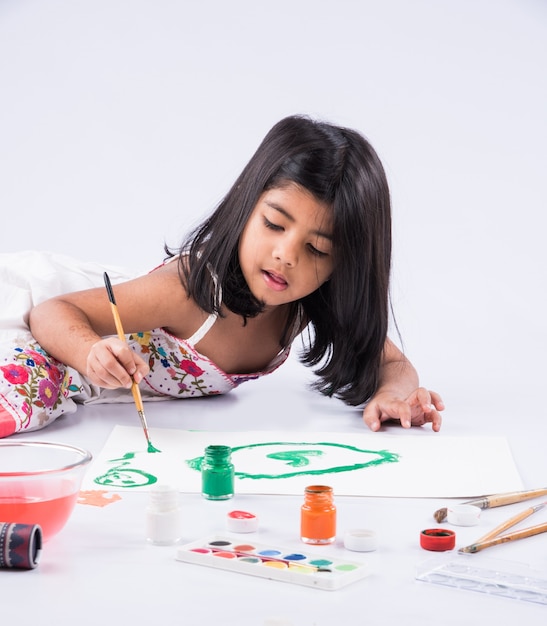 Carina bambina indiana o asiatica che si diverte a dipingere a casa con carta, acquerello e pennello artistico. Messa a fuoco selettiva
