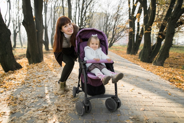 carina bambina seduta nel passeggino viola accanto a sua madre