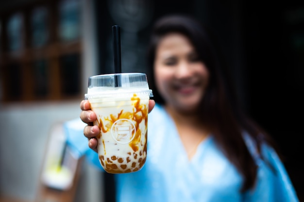 Carina donna sovrappeso in un caffè, donna asiatica felice in un caffè con una tazza di caffè in plastica