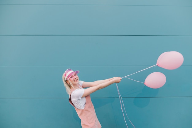 Carina giovane donna in abiti rosa in piedi con palloncini