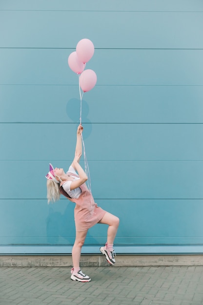 Carina giovane donna in abiti rosa in piedi con palloncini