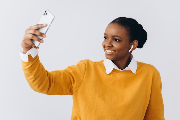 Carina giovane donna nera con eleganti dreadlocks che si fa selfie su smartphone per social media o amici, donna afroamericana positiva che si diverte a casa, usando il telefono cellulare, copia spazio
