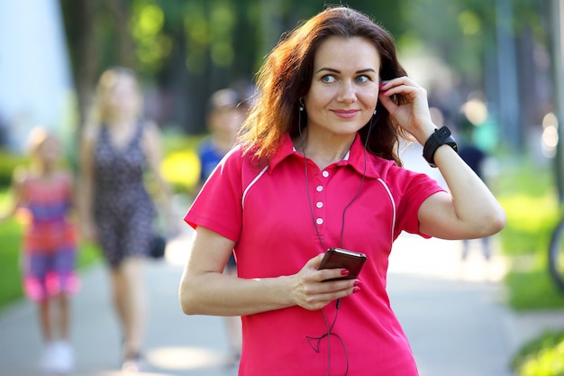 Carina giovane donna sportiva che ascolta la musica in una passeggiata