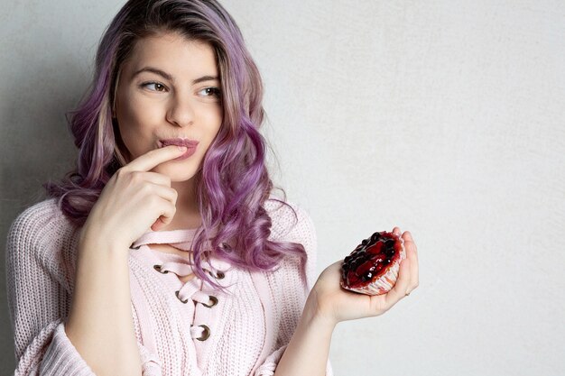 Carina giovane modella con i capelli viola che si gode un gustoso dessert con frutti di bosco. Spazio per il testo