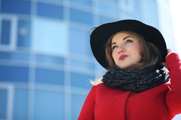 Carina imprenditrice con un cappotto rosso su uno sfondo di grattacieli