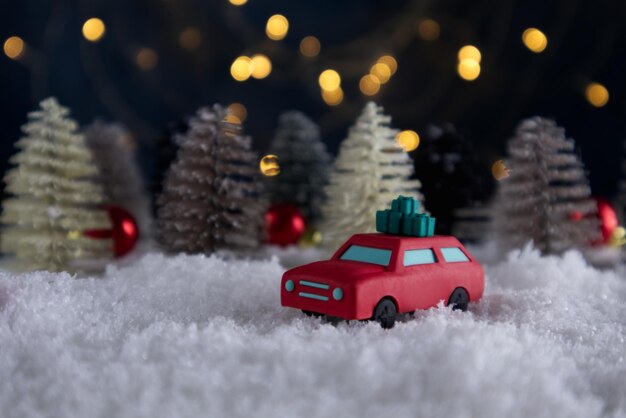 Carina macchina rossa con regali sul tetto sotto la nevicata nella foresta invernale da favola