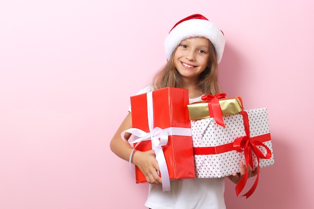 Carina ragazza allegra con un cappello di natale su uno sfondo colorato con in mano un regalo