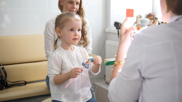 Carina ragazza bionda con mamma in oftalmologia infantile - diagnosi optometrista vista, primo piano