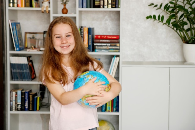 carina ragazza gioiosa che tiene un globo nelle mani sullo sfondo di una libreria