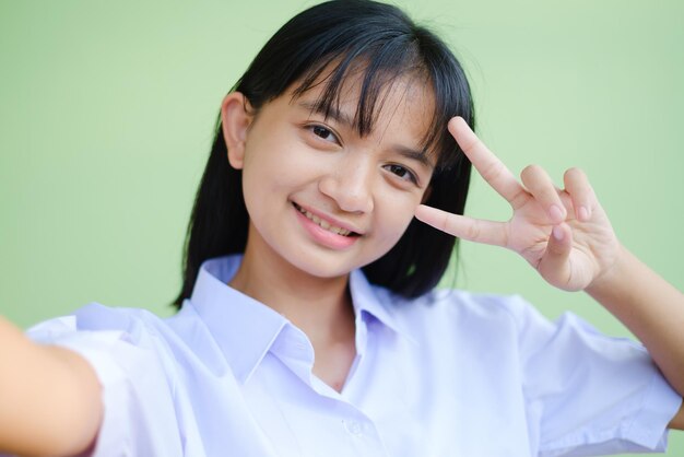 Carina studentessa fa slefie con lo smartphone, indossa l'uniforme scolastica, ragazza asiatica.