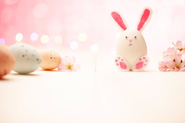 Carine uova di coniglio di Pasqua e fiori su uno sfondo rosa pastello Fiore di coniglio primaverile