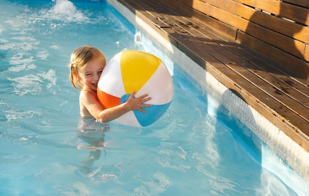 Carino abbastanza giocoso felice bionda caucasica ragazza di due anni childkid bambino che gioca con la palla divertendosi con l'acqua all'aperto in estate piscinaCareless infanzia tempo libero stile di vita